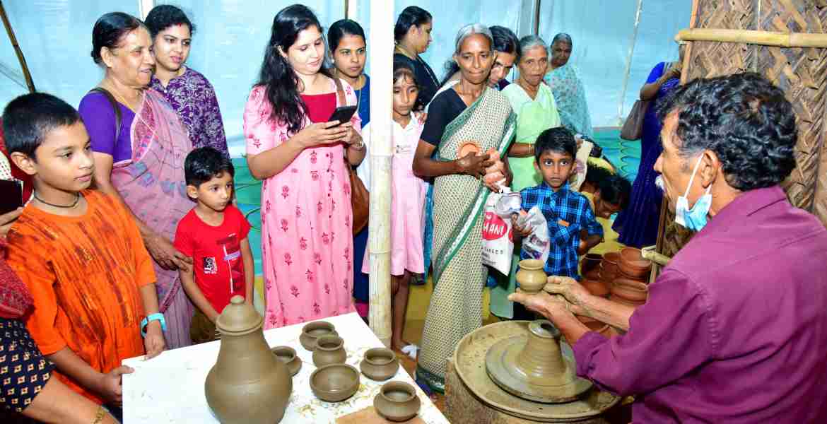 സംസ്ഥാന സർക്കാരിൻ്റെ നാലാം വാർഷികം എൻ്റെ കേരളം പ്രദർശന വിപണന മേളയിലെ ഉത്തരവാദിത്ത ടൂറിസം പവലിയനിൽ  മൺപാത്രങ്ങൾ നിർമ്മിക്കുന്നത് നോക്കി കാണുന്ന സന്ദർശകർ
